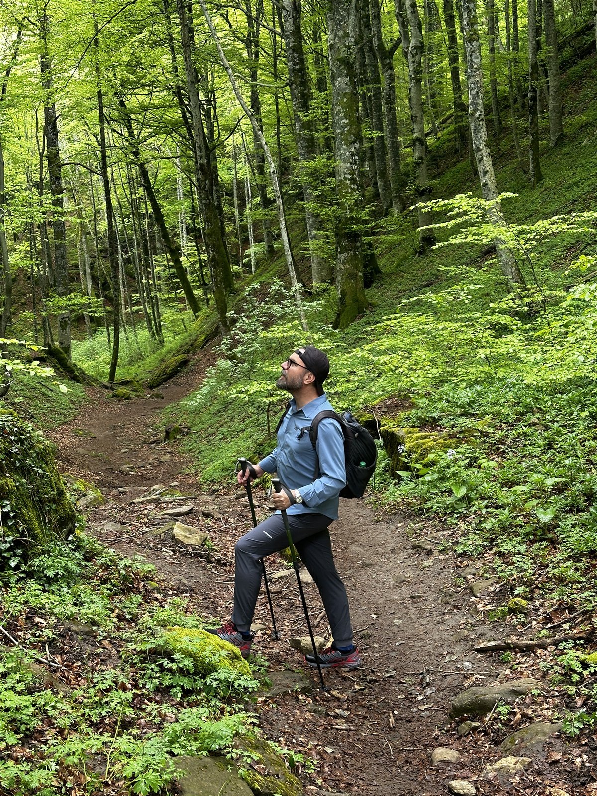 Gerry Grassi con zaino e bastoncini su un sentiero nel bosco